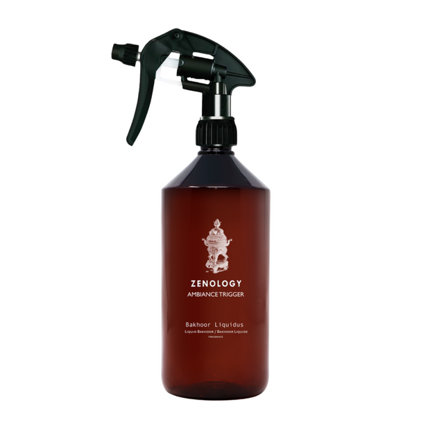 ROOM SPRAY BAKHOOR A brown room spray bottle with a label featuring an illustration of a face and the text 'ZENOLOGY AMBROSIA TRIGGER', indicating the fragrance of the product.